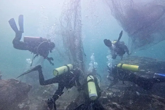 Divers removing ghost nets underwater in Hong Kong seabed cleanup operation